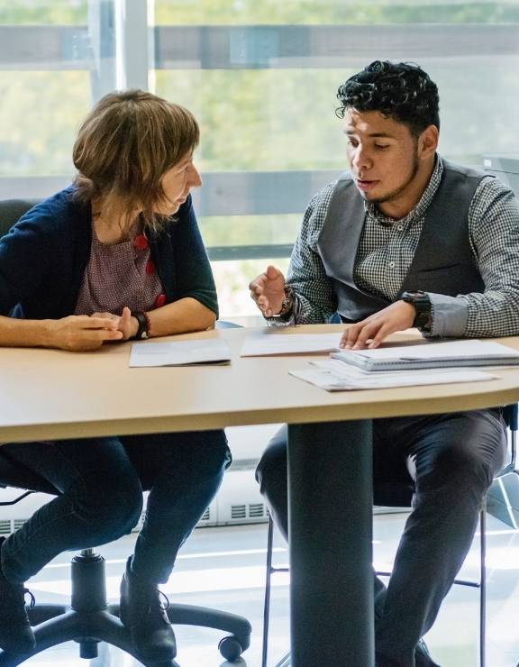 Two people talking at a desk